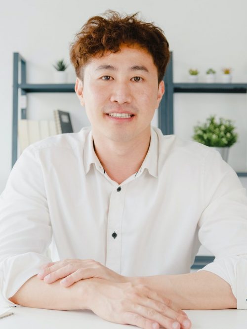 asian businessman using laptop talk to colleagues in video call meeting while working from home e1654066133616